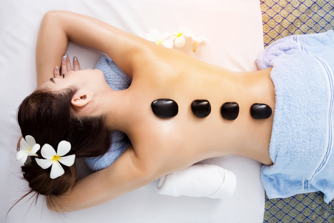 Hot stone on back of asian pretty woman in spa room